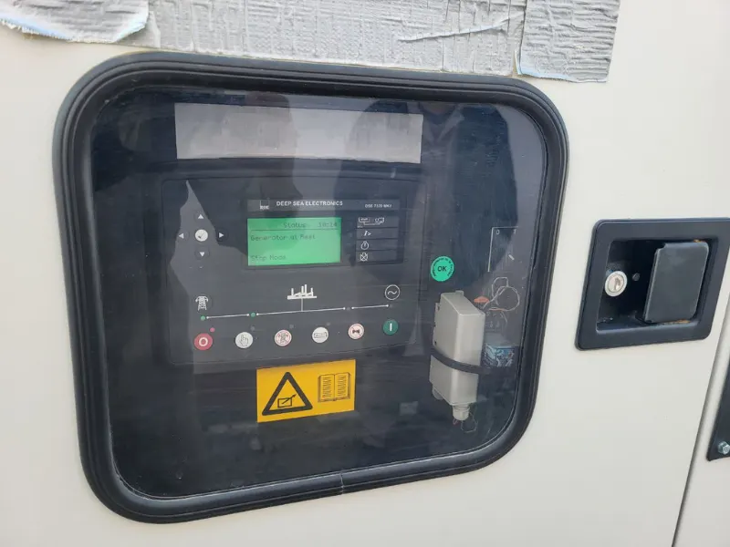 Deep Sea Electronics controller behind the window in the generator door: the screen shows “Generator at Rest”, with the start and stop buttons below.